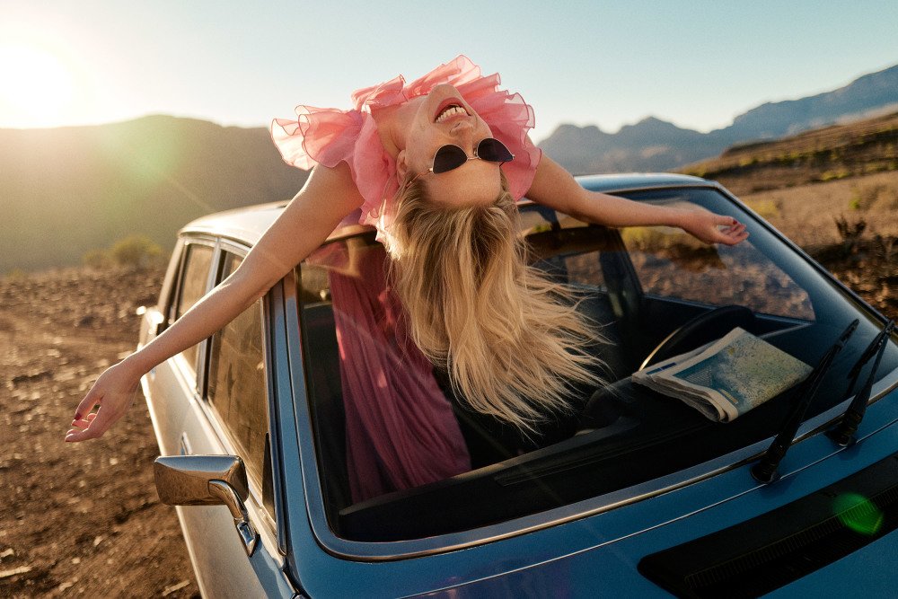 Kvinne på taket av en bil med solbriller
